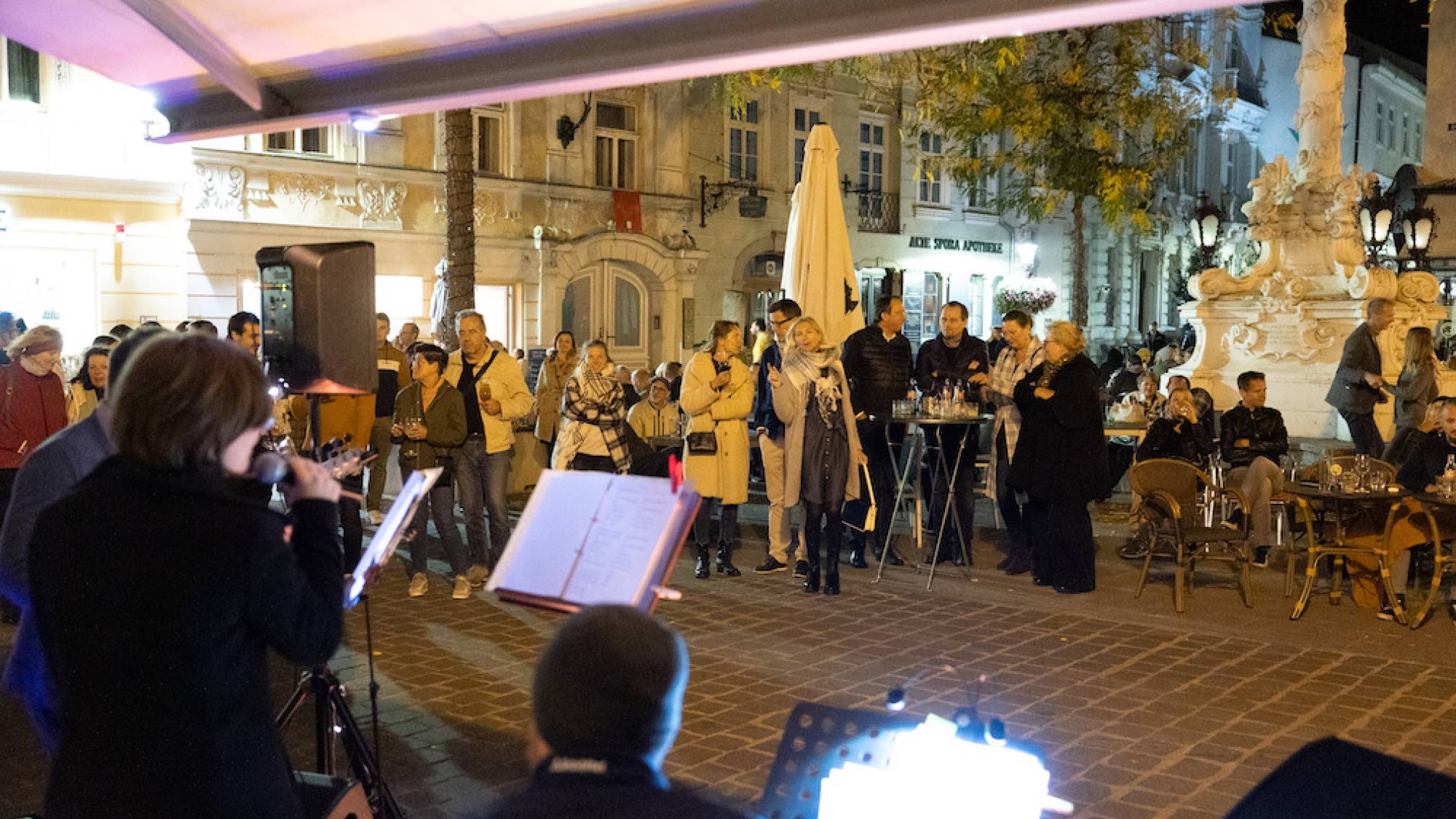 Zahlreiche Menschen stehen abends vor dem Weinlokal Vino in der schön beleuchteten St. Pöltner Innenstadt. Foto: Patrick Salfinger Fotografie